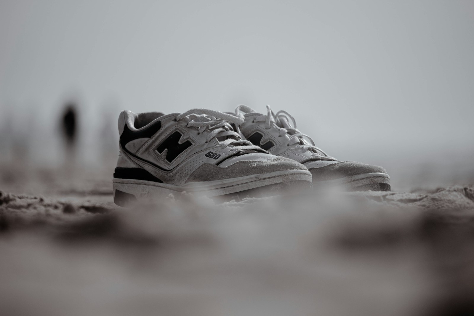 New balance sneakers rest on the beach.